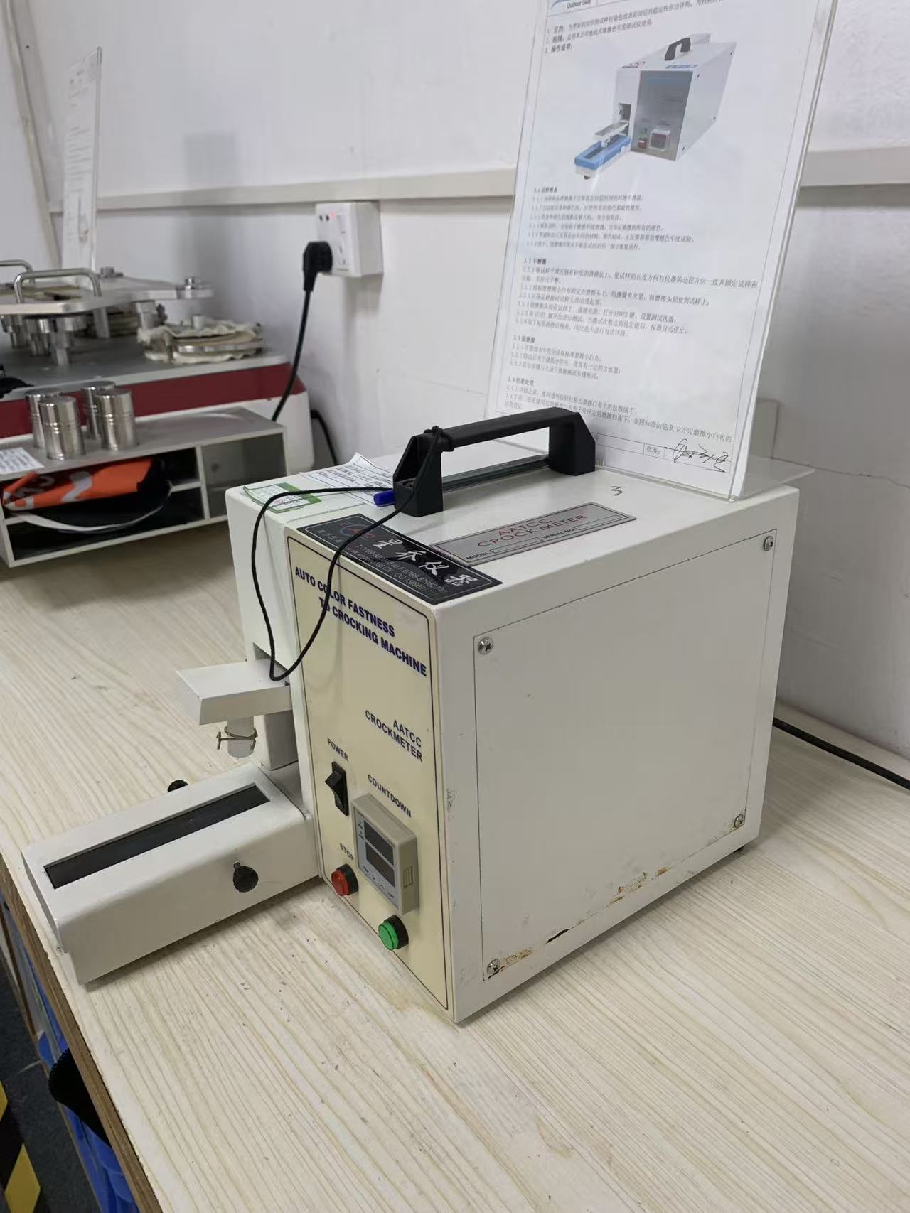 The crockmeter on the lab bench beside other test equipment